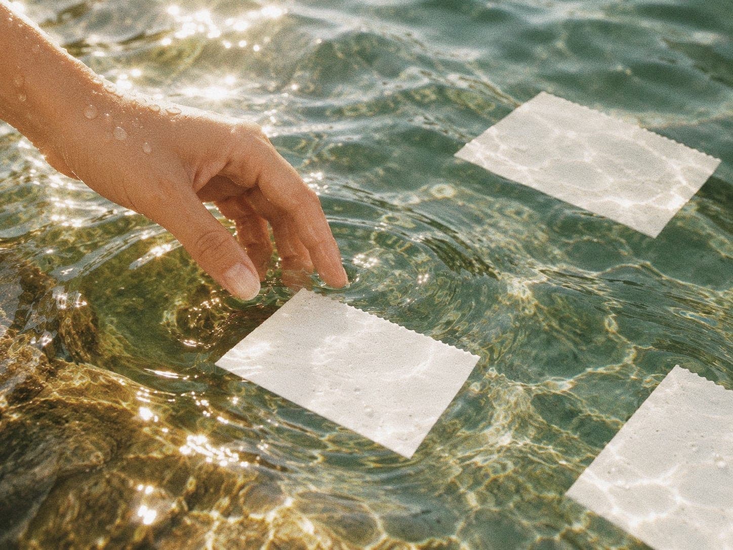 Drie bibi wasstrips die in helder water liggen, met een hand die het water raakt